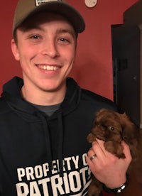 a young man holding a small brown puppy