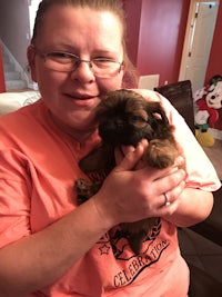 a woman holding a small brown puppy