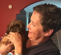 a woman holding a small brown dog in her arms