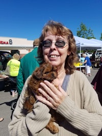 a woman holding a small brown dog