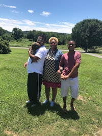 three people posing for a picture in a grassy field