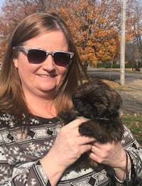 a woman in sunglasses holding a brown puppy