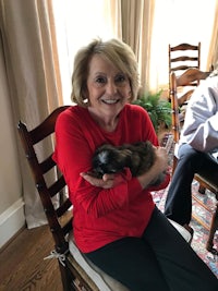 a woman sitting in a chair holding a small puppy